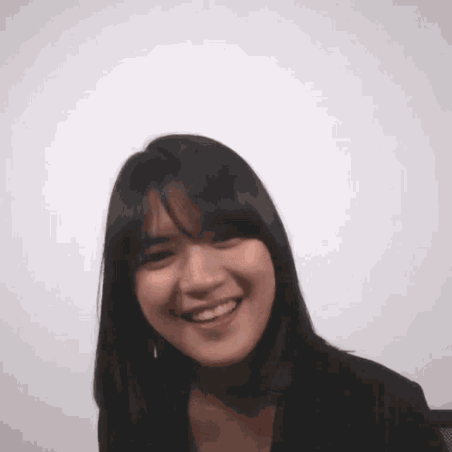 a young woman with black hair and bangs is smiling for the camera