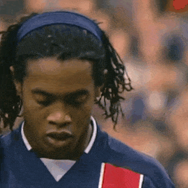 a close up of a soccer player wearing a headband and a blue jersey