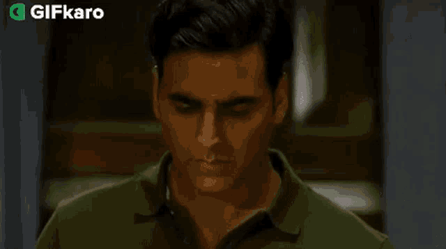 a man in a green shirt is making a serious face .