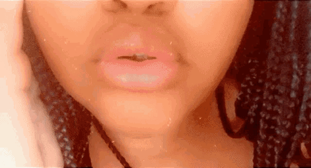 a close up of a woman 's lips with pink lipstick and a black necklace .