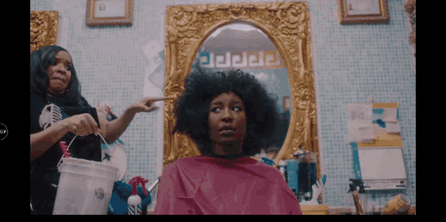 a woman getting her hair cut in front of a mirror with a greek key pattern