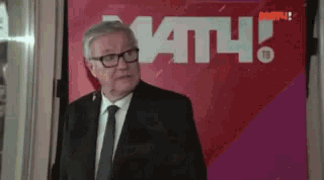 a man in a suit and tie stands in front of a sign that says mtv .