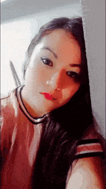 a woman in a pink shirt is leaning against a wall and looking at the camera