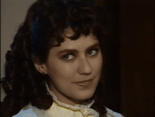a woman with curly hair and a white shirt smiles