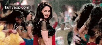 a woman in a red saree is dancing in a crowd .