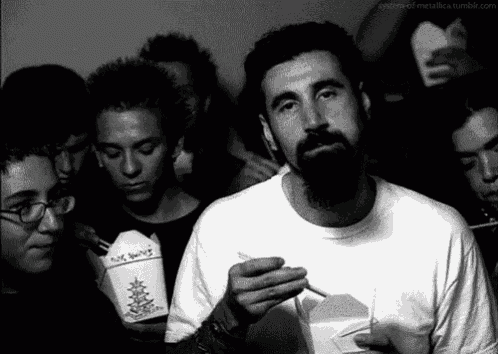 a man with a beard is smoking a cigarette while holding a box that says no smoking