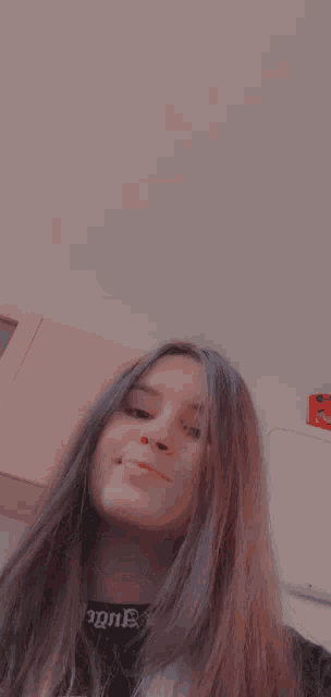 a girl with long hair is taking a selfie in front of a wooden cabinet .