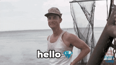 a man in a white tank top is standing in front of a body of water and says hello