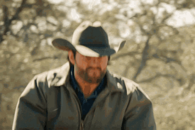 a man with a beard wearing a cowboy hat and a jacket
