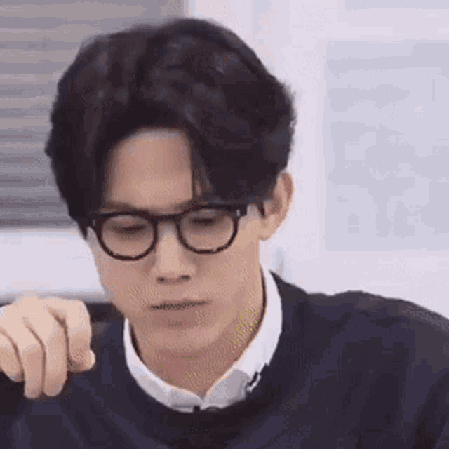 a man wearing glasses and a sweater is sitting at a table .