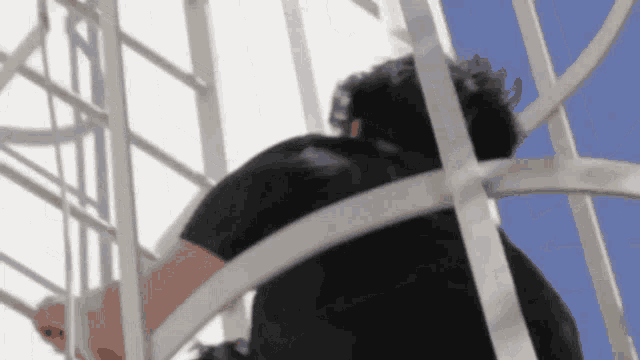 a man in a black shirt is climbing up a metal structure