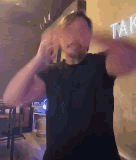 a man in a black shirt is covering his ears in front of a taco sign