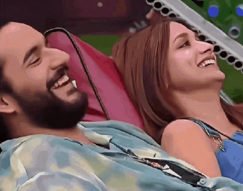 a man and a woman are laughing together while laying on a couch