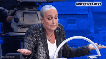 a woman in a sequined jacket is sitting at a table with her hands outstretched in front of a camera ..