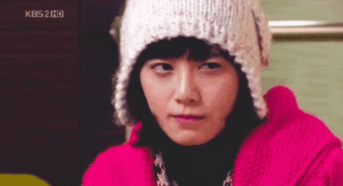 a woman wearing a pink jacket and a knitted hat is looking at the camera .