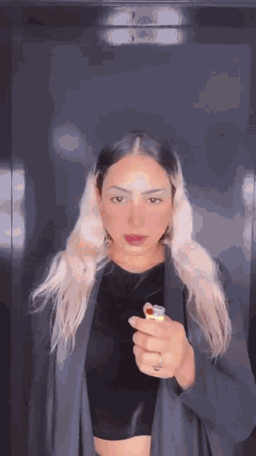 a woman is holding a lighter in her hand and smoking a cigarette .