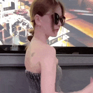 a woman wearing sunglasses is standing in front of a television screen .