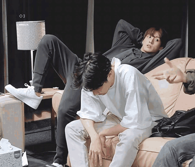 a man laying on a couch with his legs crossed and a box of kleenex in front of him