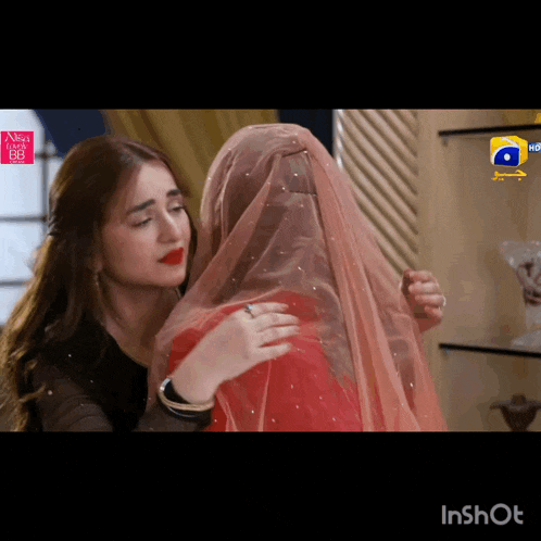 a woman in a red dress is hugging another woman in a black dress