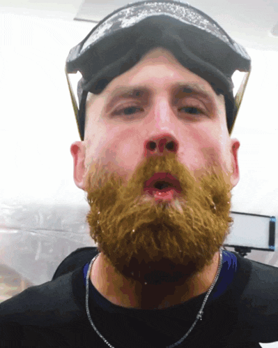 a man with a beard wearing a black shirt and goggles