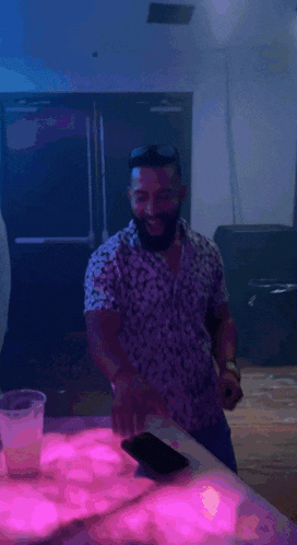 a man with a beard wearing a floral shirt is smiling