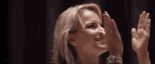 a close up of a woman applauding with her hands up .