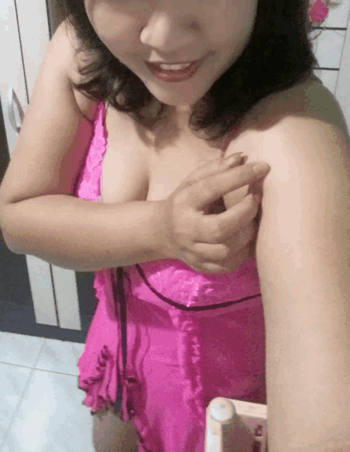 a woman in a pink dress takes a picture of herself