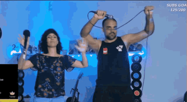 a man and a woman are singing in front of a screen that says subs goa 125/200