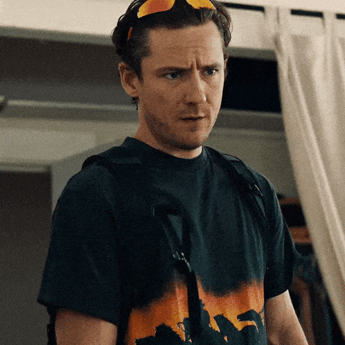 a man wearing sunglasses and a black t-shirt with a picture of a dinosaur on it
