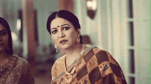 a woman with a bindi on her forehead is wearing a necklace and earrings