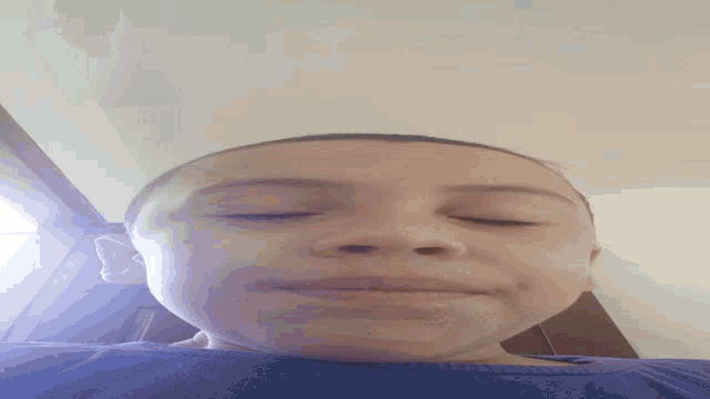 a young boy with his eyes closed and a blue shirt on