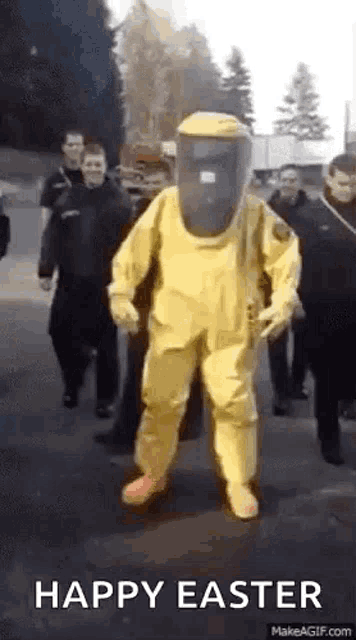 a man in a yellow hazmat suit is walking down a street .