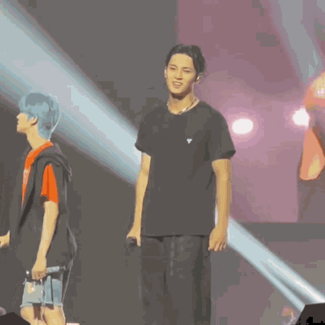 a man in a black shirt with a triangle on it stands on a stage