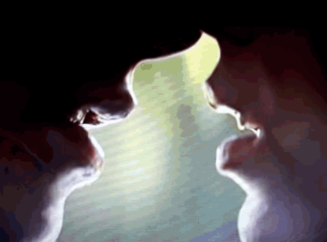 a close up of two people 's faces looking at each other in a dark room