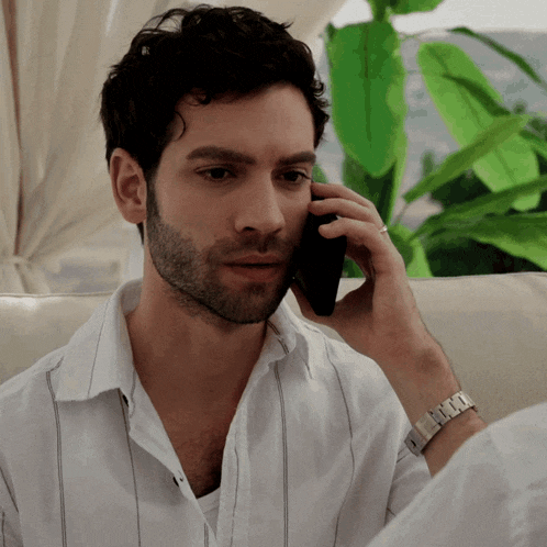a man talking on a cell phone with a watch on his wrist