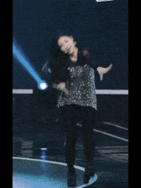 a woman is dancing on a stage in front of a blue background