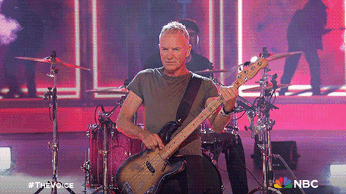 a man playing a guitar in front of a drum set with the nbc logo in the corner
