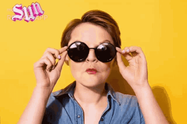 a woman wearing sunglasses against a yellow background with the word sun written in pink