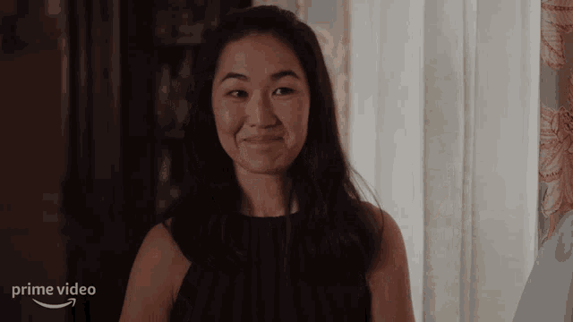 a woman is smiling in front of a screen that says prime video on it
