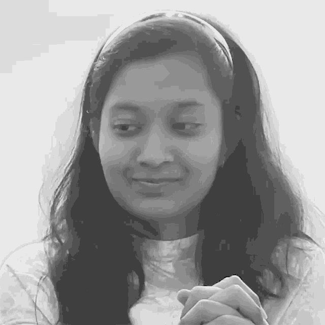 a black and white photo of a young woman with her hands folded