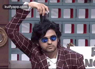 a man wearing sunglasses is brushing his hair with a comb .