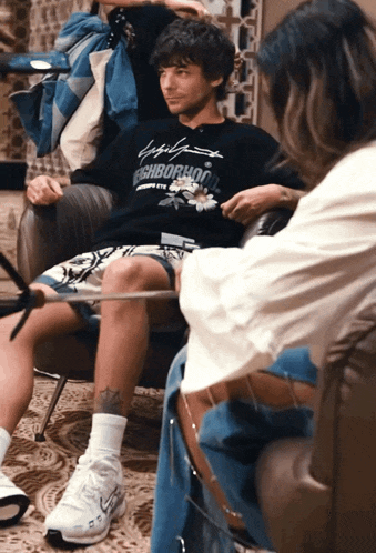 a man sitting in a chair wearing a neighborhood sweatshirt