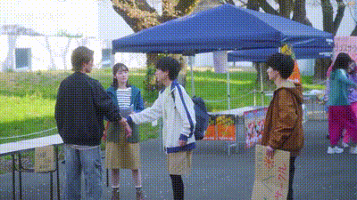 a group of people are standing under a blue tent .