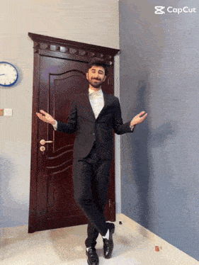 a man in a suit is standing in front of a door with a clock on the wall behind him
