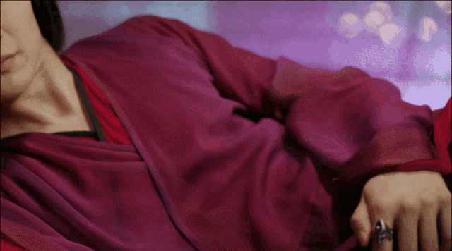 a woman wearing a ring on her finger is laying on a bed