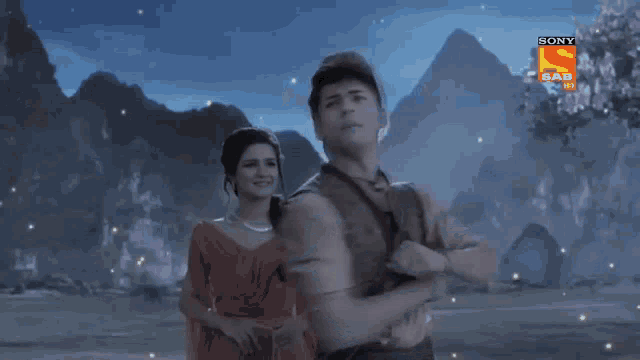 a man and a woman are dancing in front of mountains and a sign that says sony sab hd