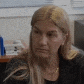a woman with blonde hair is sitting at a desk in front of a computer .