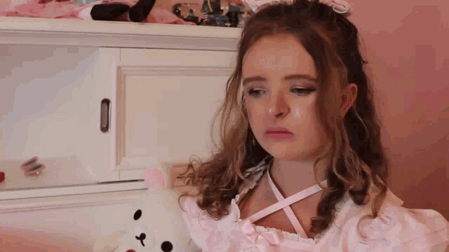 a girl in a pink dress is holding a stuffed bear