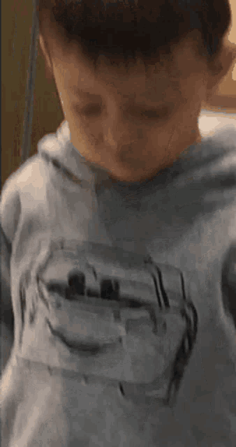 a young boy wearing a grey hoodie with a picture of lightning mcqueen on it