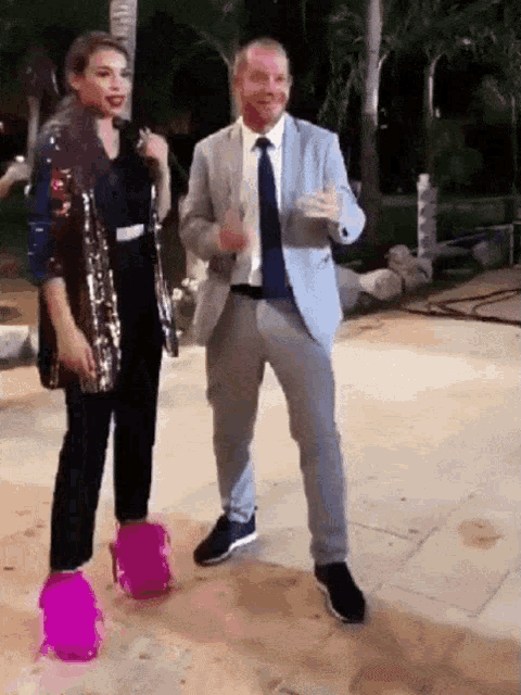 a man in a suit and tie is dancing with a woman in pink shoes